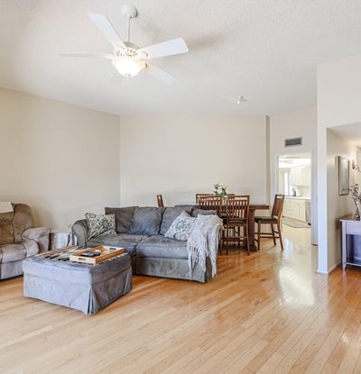 Open living and dining area with hardwood flooring, ceiling fan, and easy flow into the kitchen, ideal for gatherings and daily living.