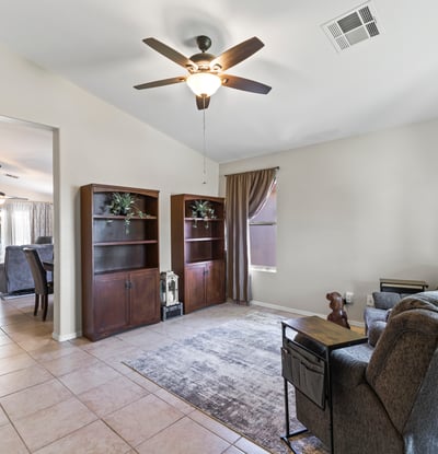 Spacious front living area with tile flooring, ceiling fan, and natural light. A versatile space perfect for relaxing or hosting guests.