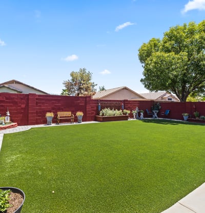 Spacious yard with artificial turf, raised garden beds, and decorative landscaping. Ideal for gardening and outdoor enjoyment.