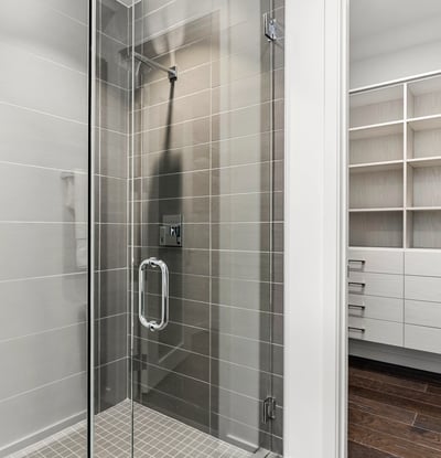Well-appointed secondary bedroom with an attached bathroom including a glass walk-in shower and convenient access to a large closet, designed for comfort and efficient living in Phoenix.