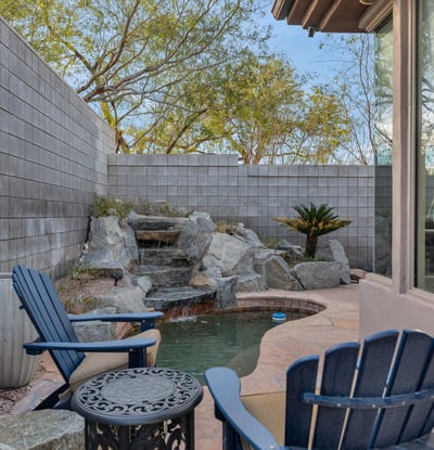 Serene backyard featuring a cascading water feature, patio seating, and low-maintenance landscaping in this Phoenix home.