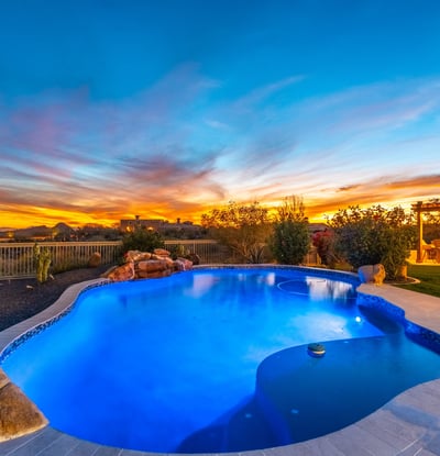 Scottsdale backyard illuminated at sunset with pool, spa, and outdoor kitchen, creating the perfect space for entertaining and relaxing evenings.