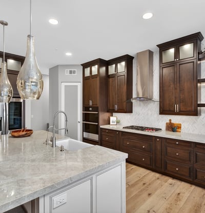 Beautifully upgraded kitchen featuring dark wood cabinetry, quartz surfaces, stainless appliances, and modern backsplash in this Scottsdale home.
