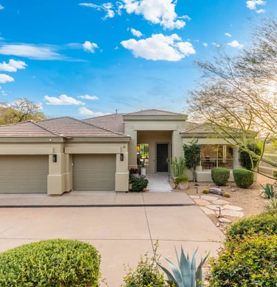 Scottsdale home exterior featuring desert landscaping, three-car garage, and welcoming entry for strong curb appeal.