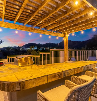 Scottsdale backyard featuring a pergola-covered bar with seating and string lights, perfect for entertaining guests.