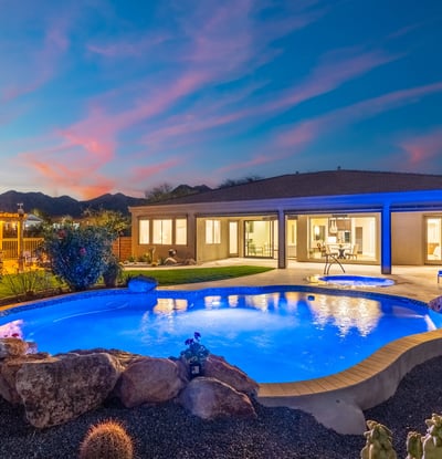 Scottsdale backyard featuring pool, spa, pergola kitchen, and desert landscaping under a dramatic sunset sky.
