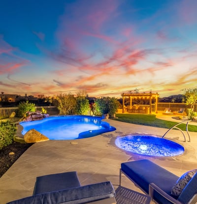 Scottsdale backyard with pool, spa, pergola, and outdoor kitchen, beautifully lit at sunset for relaxing evenings and entertaining.