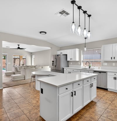 Spacious kitchen with large island, white cabinetry, and ample prep space. Open layout flows into living areas, making it ideal for gatherings in this Casa Grande property.