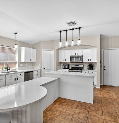 Bright open kitchen with large island, white cabinetry, and modern lighting. Perfect for entertaining and daily living in this Casa Grande home.