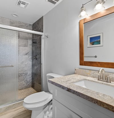 Bathroom with granite vanity, modern fixtures, and tiled shower, offering both style and practicality.