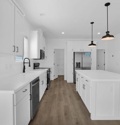 Modern kitchen showcasing an oversized island, stainless steel appliances, shaker cabinetry, and extensive workspace. Ideal for meal preparation, entertaining, and enjoying the heart of this beautifully designed home.