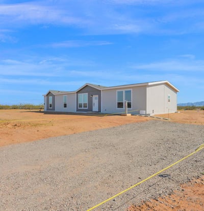 View of the home's generous acreage, gravel approach, and open desert setting. The property offers abundant space for outdoor activities, future additions, and enjoying Arizona's wide-open landscapes.