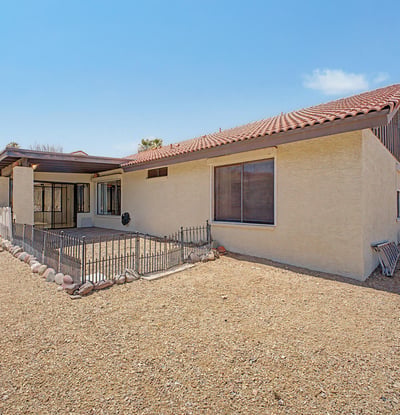 The expansive backyard showcases easy-care desert landscaping and open outdoor space. Thoughtfully designed for minimal maintenance, it offers privacy and room to enjoy Arizona's outdoor lifestyle.