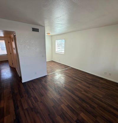 Large living room with rich wood-look flooring, neutral finishes, and a bright open feel. The spacious layout creates a welcoming environment ideal for entertaining guests or enjoying everyday comfort.