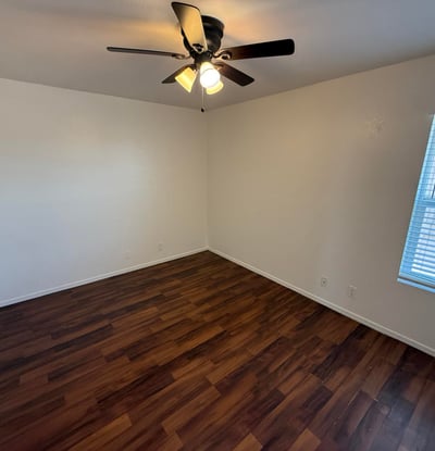 Bright and airy bedroom offering wood-look flooring, ceiling fan, and natural light. This versatile space works well as a guest room, home office, or primary sleeping area.