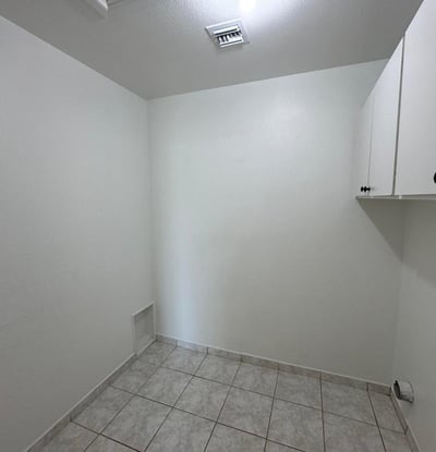 Spacious utility and laundry area featuring built-in cabinetry, durable tile flooring, and plenty of room for storage. A practical addition that supports organized living.
