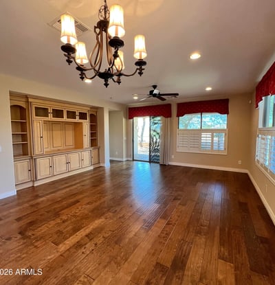 Expansive living room featuring custom built-in cabinetry, upgraded wood floors, elegant chandelier, recessed lighting, and abundant natural light. A warm and inviting gathering space designed for comfortable everyday living.