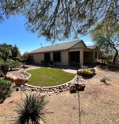 Beautiful backyard showcasing lush artificial turf, paver pathways, decorative rock features, mature desert plants, and tranquil golf course surroundings. A perfect outdoor retreat for relaxing or entertaining guests.