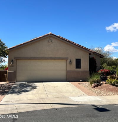 Charming front exterior with mature desert landscaping, spacious driveway, two-car garage, and attractive paver accents creating beautiful curb appeal in a desirable Buckeye neighborhood.