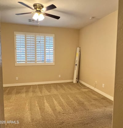 Inviting secondary bedroom featuring soft carpeting, plantation shutters, ceiling fan, and abundant natural light. Ideal as a guest suite, hobby room, or private office space.