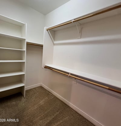 Large walk-in closet complete with built-in shelving, multiple hanging sections, and spacious storage designed to keep clothing and accessories neatly organized.