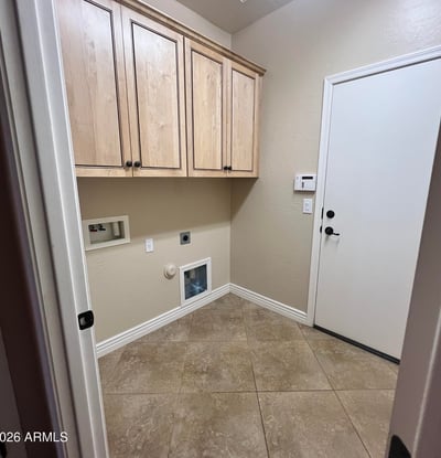 Dedicated laundry room with custom cabinetry, tile flooring, utility hookups, and extra storage space for household essentials, adding convenience to everyday living.