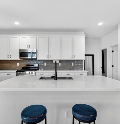 The expansive kitchen island provides casual seating, extra storage, quartz countertops, and an ideal gathering place while maintaining an open connection to the home's living areas.