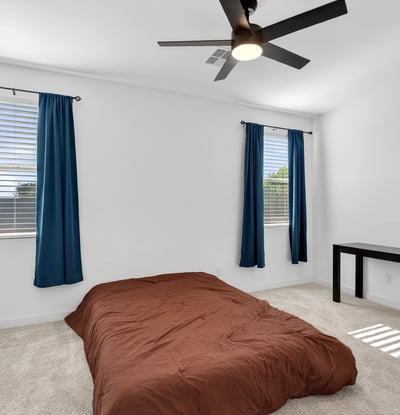 This spacious primary suite offers plush carpet, multiple windows, ceiling fan, and a relaxing atmosphere designed to provide comfort and privacy after a busy day.