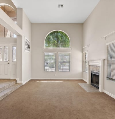 High ceilings, large arched windows, and a charming fireplace make this formal living room bright and welcoming. The spacious layout is ideal for gathering with family or entertaining guests.