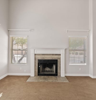 The wood-burning fireplace serves as the centerpiece of this spacious living room, complemented by tall ceilings and large windows that brighten the space. Its warm ambiance makes it the perfect place to gather with family and friends throughout the year.