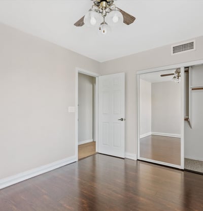 Featuring rich wood flooring, mirrored closet doors, and a ceiling fan, this spacious bedroom provides comfort, storage, and flexibility for guests or family members.