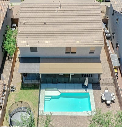 Incredible aerial perspective highlighting the sparkling pool, covered patio, custom pergola, grassy yard, and thoughtfully designed outdoor living spaces that make this Waddell home truly exceptional.