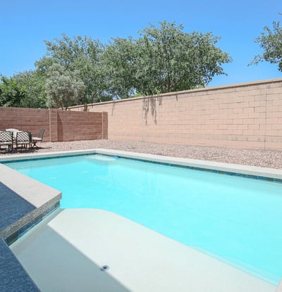 Inviting backyard pool featuring a spacious tanning ledge, modern design, and relaxing patio space. A wonderful outdoor feature that enhances the lifestyle offered by this Waddell property.