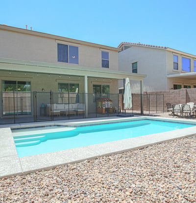 Backyard retreat showcasing a modern swimming pool, safety fence, expansive patio, and easy-care landscaping. Designed for both relaxation and entertaining at this Waddell property.