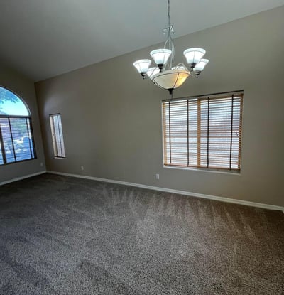 The expansive formal living area features dramatic vaulted ceilings, oversized picture windows, plush carpeting, and flexible space perfect for entertaining or everyday living.