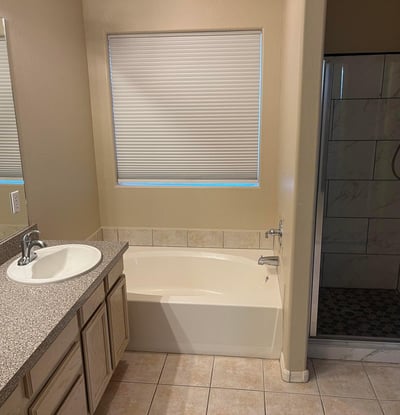 The spacious primary bath offers dual vanities, a soaking tub, an updated walk-in shower, and plenty of natural light, creating a comfortable retreat after a long day.
