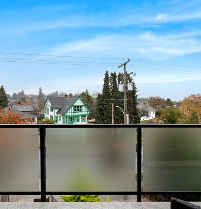 Enjoy panoramic views from this balcony, overlooking picturesque homes and lush greenery in a vibrant neighbourhood.