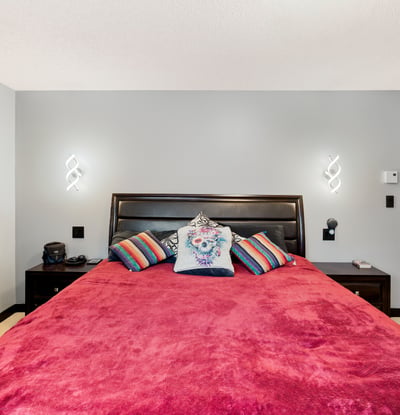 Spacious bedroom featuring a vibrant color palette, modern lighting, and ample storage for a cozy retreat.