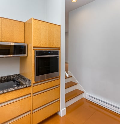 Modern kitchen features sleek cabinetry, high-end appliances, and an open layout leading to inviting stairs.