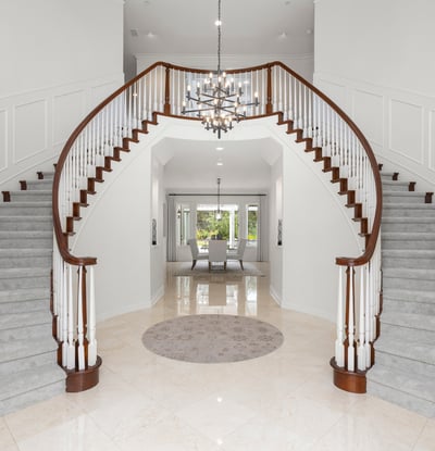 Grand foyer with dual staircases and a modern chandelier, creating an impressive first impression.