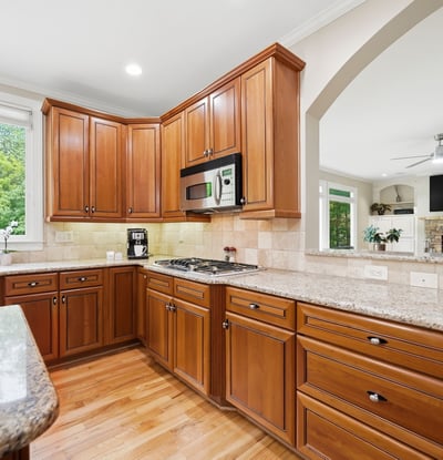 This spacious kitchen features rich cabinetry, granite countertops, and ample natural light, perfect for culinary enthusiasts.