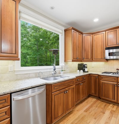 Bright kitchen featuring custom wood cabinetry, modern appliances, and ample counter space overlooking a lush outdoor view.