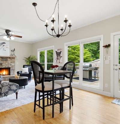 Spacious living area features a cozy fireplace and direct access to a private deck surrounded by greenery.
