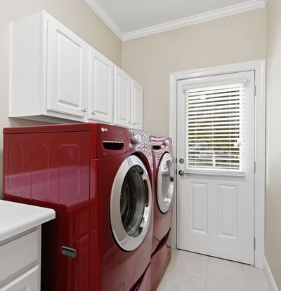 Bright and functional laundry room featuring modern red appliances and ample storage space.