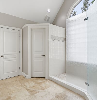 Modern bathroom featuring a spacious walk-in shower with frosted glass and natural light.