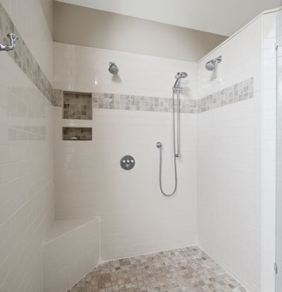 Spacious, modern shower with multiple showerheads and built-in shelving, ideal for a refreshing experience.