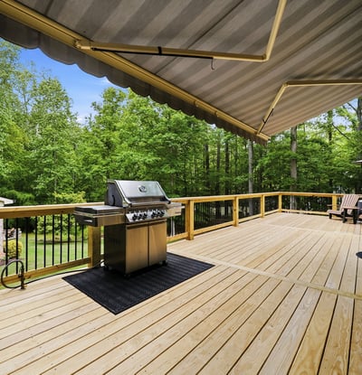 Expansive deck with built-in grill, surrounded by lush greenery, perfect for outdoor gatherings and relaxation.