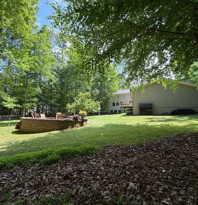 Spacious yard surrounded by lush trees, perfect for outdoor gatherings and entertaining in a private setting.