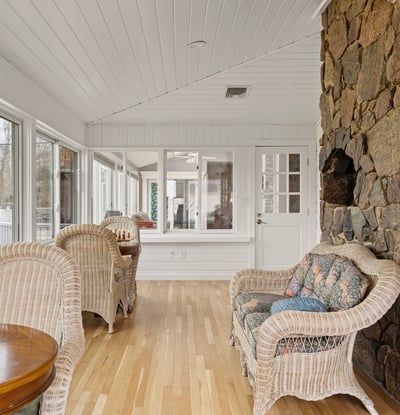 Light-filled sunroom featuring a stone wall, perfect for relaxation or entertaining with expansive views.