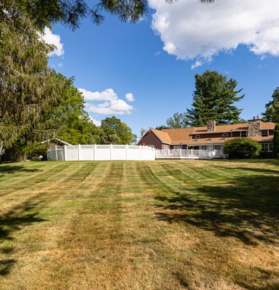 Spacious property featuring a wide-open lawn and a large, inviting home surrounded by lush greenery.